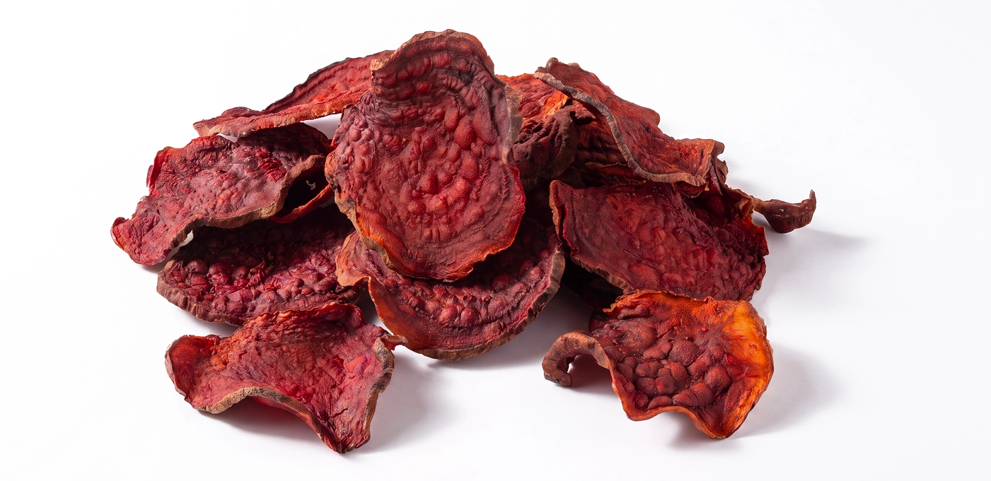 A pile of deep-red beetroot crisps on a white surface
